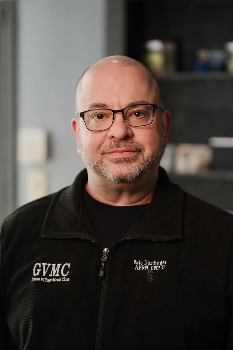 Eric Dardinger in a black GVMC fleece embroidered with his name and credentials, photographed inside the clinic.
